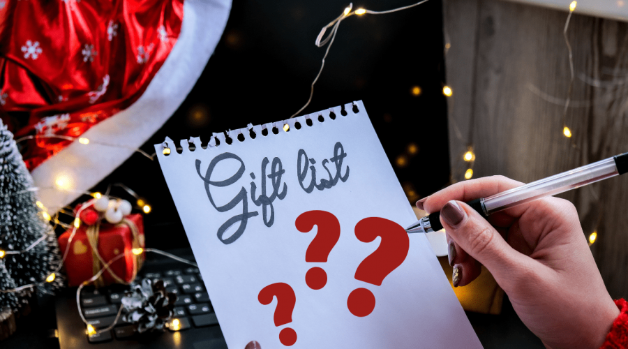 Notepad that says Gift List with question marks as woman's hand with pen hovers over it.