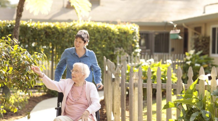 a lady walking an senior woman in a wheelchair