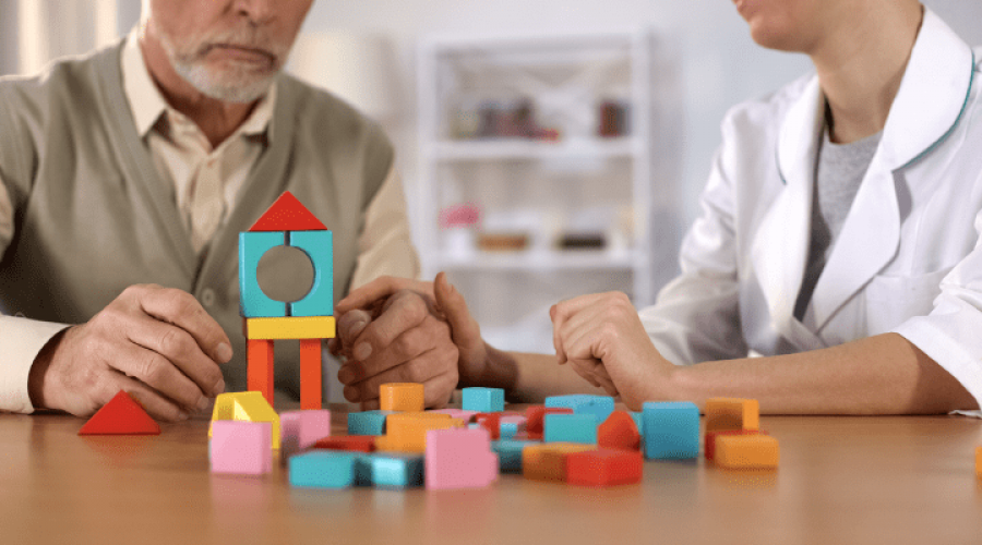 A nurse and an older adult assembling blocks.