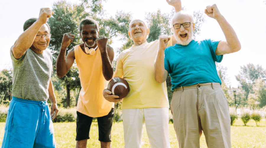 A group of older adults cheer while standing outside.